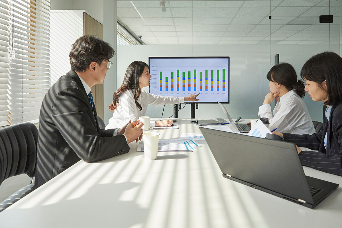 Business team in a sunlit conference room reviewing a bar chart on a large screen